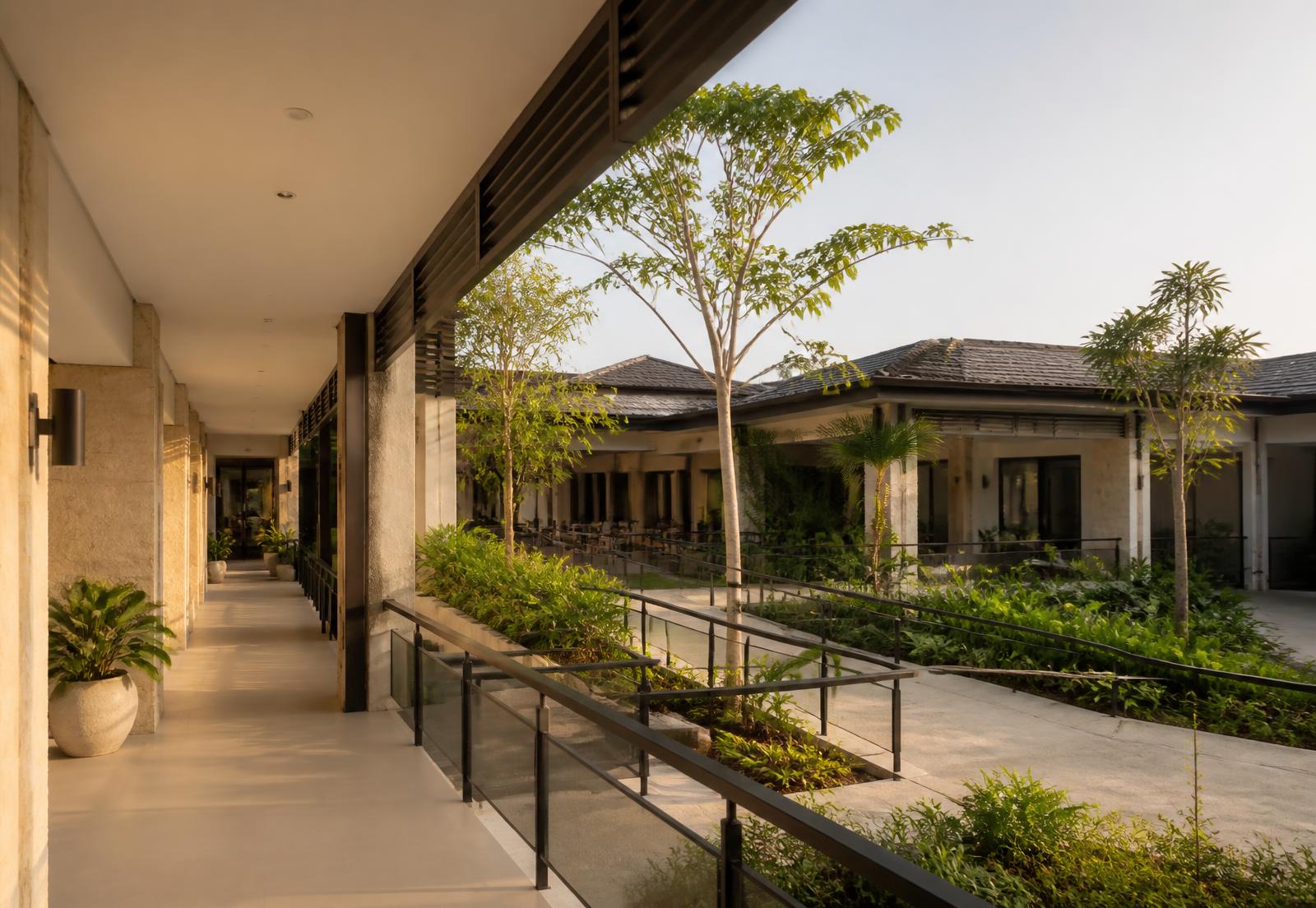 Shaded accessible walkway with gentle ramps and handrails in a low-rise Philippine senior living community